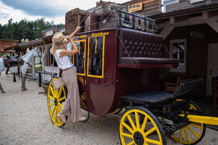 Zlatibor, Vodice, Serbia - July 26. 2020 Woman on cowboy wooden wagon in the city of El Paso in wild west style and cowboy style. Western thematic park. Travel conceptのeditorial素材