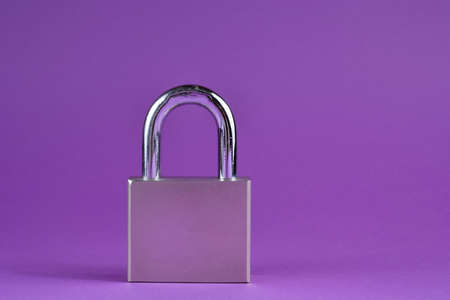 Big metal padlock in silver metallic color isolated on purple background with copy spaceの写真素材