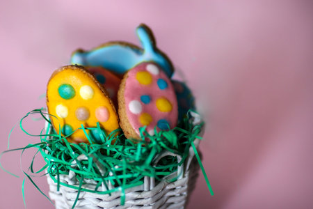 Easter cookies in the shape of a rabbit and colorful eggs isolated on pink background. Easter...