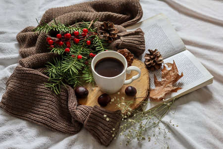 Cup of coffee and woolen sweater on a bed with yellow fall leaves and open book. Autumn concept decoration background. Close up, selective focusの写真素材