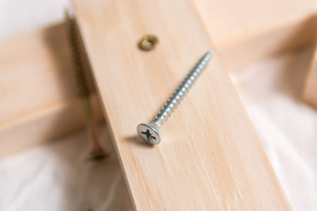 Metal screw on a wooden plank in carpenters workshop. Close up, selective focus, and copy space