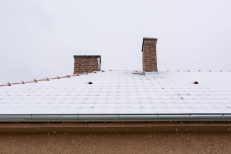 Roof with chimneys on the house covered with snow on a cold winter morning