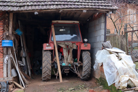 Dragovlje, Serbia - January 09. 2022 Village shed with a tractor inside and various agricultural toolsのeditorial素材