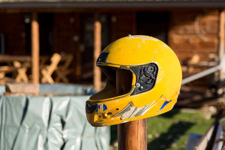Yellow broken motorcycle helmet attached to a wooden stake outdoor. Close up, selective focusの写真素材