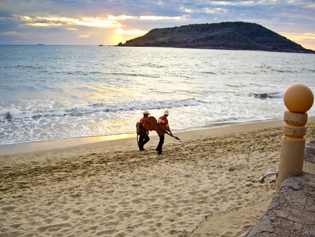 MAZATLAN, SINALOA/MEXICO  FEBRUARY 7: Two Mariachi musicians stroll on beach at sunset carrying their instruments heading for the next tourist performance shown on February 7, 2010 in Mazatlanのeditorial素材