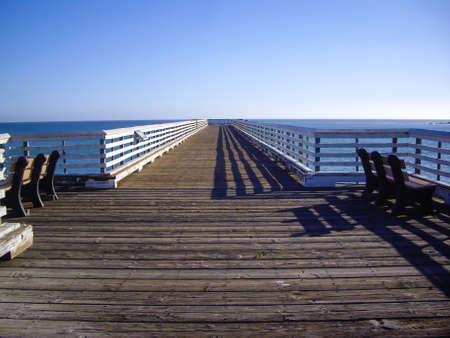 Long pier with two benches at coastの写真素材