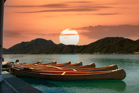Sunset on the lake with traditional wooden canoe and mountain background, South Koreaの写真素材