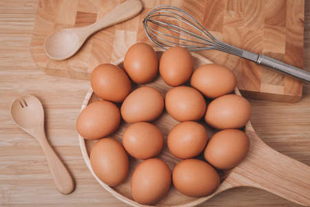 Top view of eggs in wooden dish with wooden Spoon and fork on wood table.の写真素材
