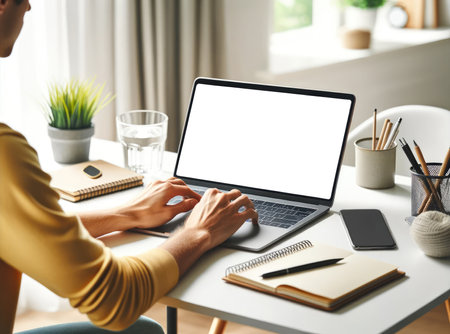 Individual working on a laptop at a tidy workstation with a notepad, pen holder, and decorative plant, depicting a productive setting.の素材