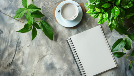 Cup of coffee and notepad with green plant on grey backgroundの素材