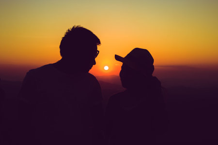 Silhouette of happy a couple standing face to face behind sunsetの写真素材