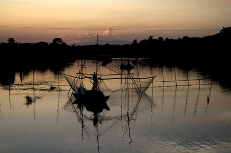 Fishermen silhouette on the river at sunset,Thailand.の写真素材