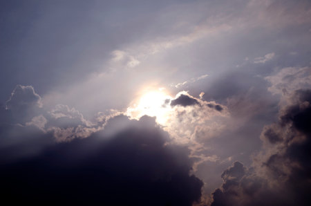 Sunset sky with clouds and rays of light shining through the cloudsの写真素材