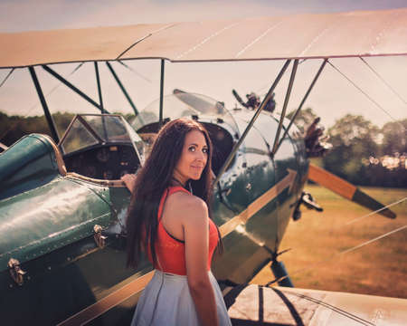 Woman waits by antique airplane.の写真素材