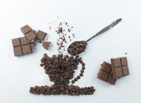 Coffee cup and chocolate pieces on white background, top view