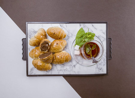 Top view of fresh baked croissants with chocolate and mint on white and brown backgroundの写真素材