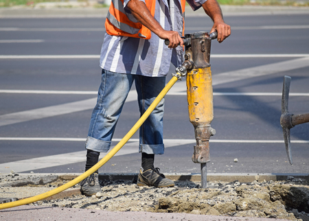 Man works with an air hammer at the road constructionの写真素材