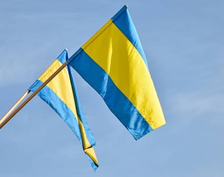 Blue and yellow flags against skyの写真素材