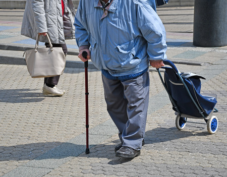 Old man with a wheeled shopping bag on the streetの写真素材