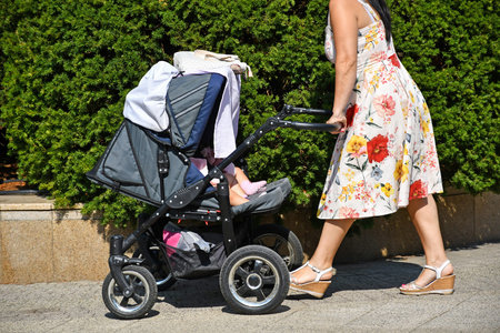 Woman pushes a baby carriage on the city street