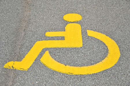 Yellow disabled sign on the asphalt of the streetの写真素材