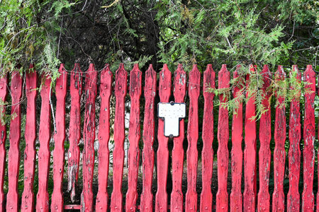 Old red wooden fence and green leavesの写真素材