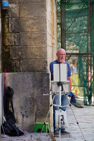 Kotor - Montenegro - 17th of july 2016. Full length portrait of a senior artist standing next to a stone wall on the street of Old Townのeditorial素材