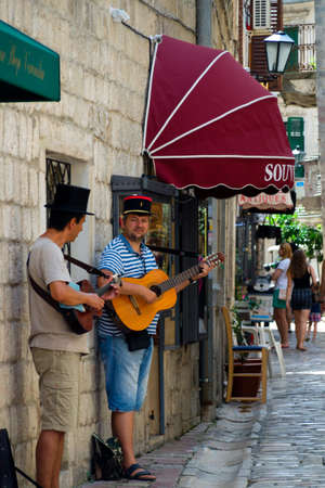 Kotor - Montenegro - 17th of July 2016. Two street performers in hats with guitar, with a stone wall in the backgroundのeditorial素材