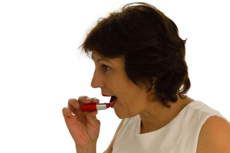 Beauty senior woman in white dress apply lipstick. Studio shot on white backgroundの写真素材