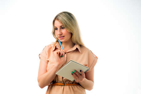 Portrait of beautiful young blonde woman thinking with a notepad, isolated on white background. Studio shootの写真素材
