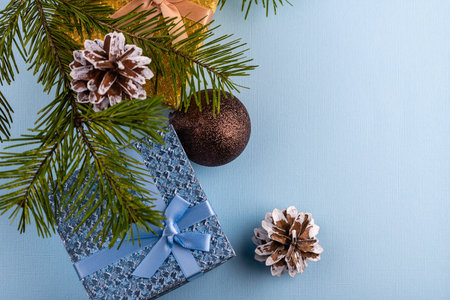Fir branches, Christmas balls, gifts and cones on a blue background. Christmas background, top view....
