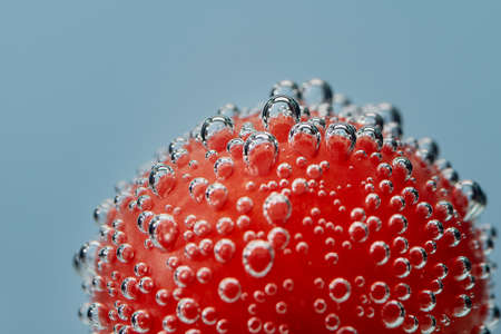 Air bubbles on a red object under water. Horizontal Studio photo on a blue background. Macro modeの写真素材