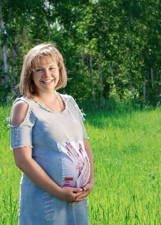 Happy beautiful pregnant woman in nature in summerの写真素材