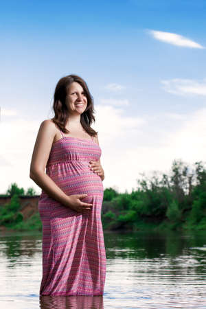 Happy beautiful pregnant woman in nature in summerの写真素材