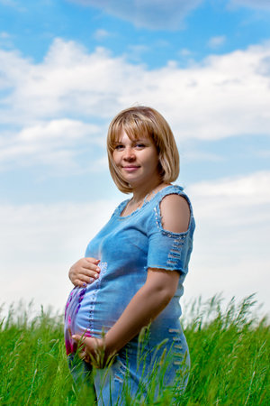 Happy beautiful pregnant woman in nature in summer