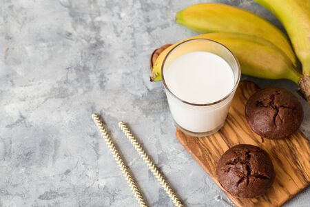 Homemade chocolate muffins with powdered sugar, glass with milk. Grey background の写真素材