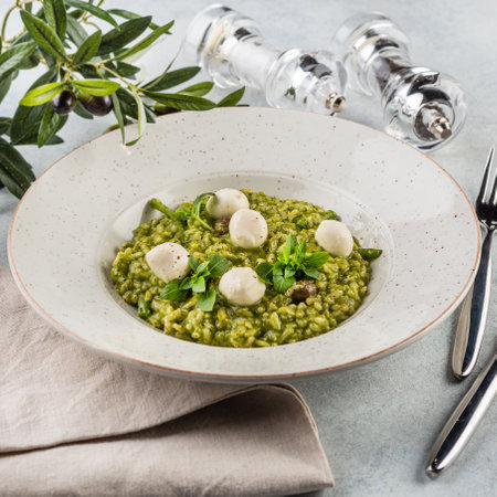 Green risotto with spinach and basil pesto. White plate on a white light background.の写真素材