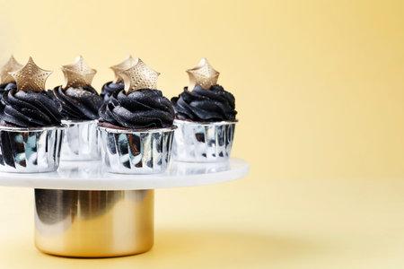 Black cupcakes decorated with a gold star on a cake stand