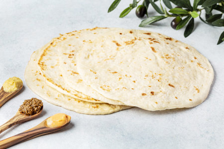 fresh pita bread and dips on a white stone board, top view