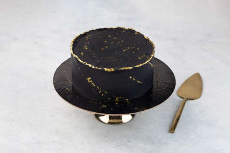 Chocolate cake with black icing, decorated with gold sequins on a white background. A picture for a menu or a catalog of confectionery products.の写真素材
