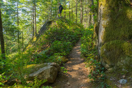Hiker climbs up and down large granite boulders along trailの写真素材