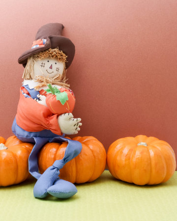 Happy scarecrow sits on pumpkinsの写真素材