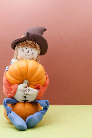Smiling Scarecrow Holds A Pumpkin While Sitting Downの写真素材