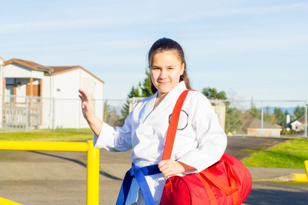 Young Female Martial Arts Student Waves Helloの写真素材