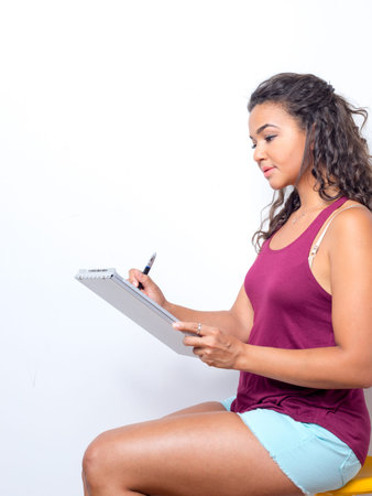 Attractive young woman of color holds a pen and clipboardの写真素材