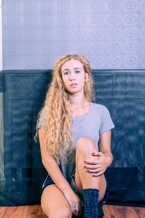 Cute blue eyed American female sitting on floorの写真素材