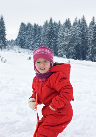 Little girl staying in the snow and her hand is cold