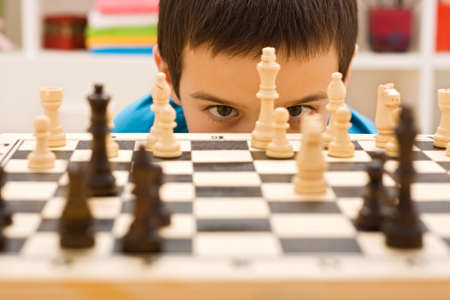 Boy looking at piece of chessの写真素材