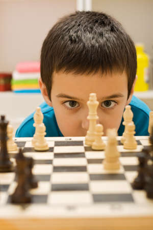 Boy looking at piece of chessの写真素材