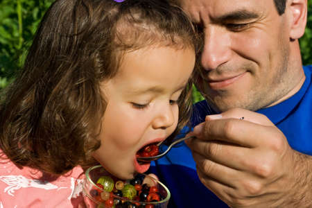 Father giving fresh fruits to his little girlの写真素材